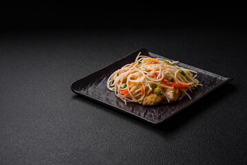 Tasty dish of Asian cuisine with rice noodles, chicken, asparagus, pepper, sesame seeds