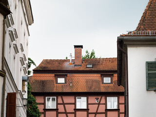 Half timbered building exterior in a town. The rooftop and the exterior are weathered and dirty. The old house is part of a residential district. The traditional architecture is a tourist attraction.