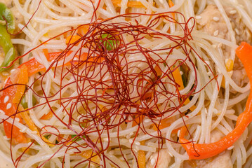 Tasty dish of Asian cuisine with rice noodles, chicken, asparagus, pepper, sesame seeds