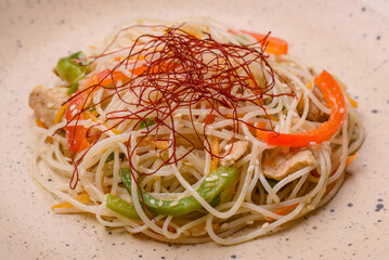 Tasty dish of Asian cuisine with rice noodles, chicken, asparagus, pepper, sesame seeds