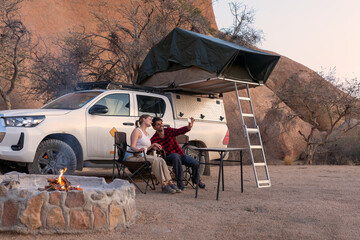 camping, tourism and travel concept - happy couple with smartphone taking selfie at tent camp