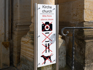 Etiquette when entering a church. The information sign at the entrance shows rules like be silent, don't take photos, no mobile phone, no eating and no dogs allowed.