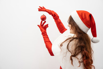 An isolated shot of a young woman with a Christmas ball gives a sense of magic and fun. In the...