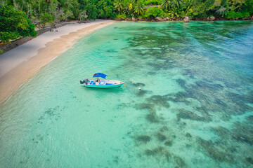 Drone of baie lazare beach, docking fisherman boat on low tide near the shore, turquoise water, sunny day, Mahe Seychelles 