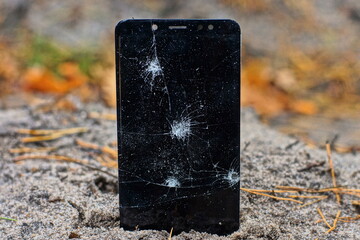 modern new glass broken with cracks black screen of a mobile touch phone in the ground on the street during the day
