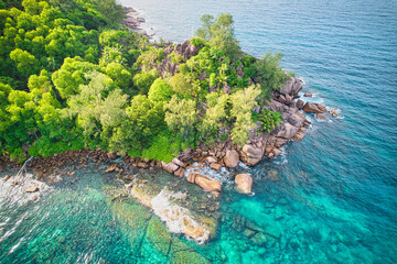 Drone of baie lazare beach, granite stones, turquoise water, coconut palm trees on hill, sunny day, Mahe Seychelles 1