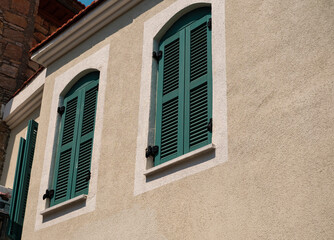 Fototapeta na wymiar green wooden new painted window shuts in mediterranean european style, street view house wall exterrior