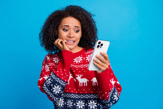Photo of attractive nervous afraid scared girl wear trendy ornament jumper biting lips reading news isolated on blue color background
