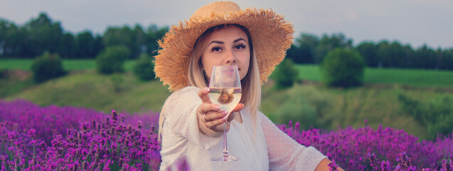 A woman drinks wine in a lavender field. Selective focus.
