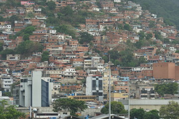 Fototapeta na wymiar Suburb of La Guaira town near Caracas with poor family houses showing poverty and is situated on hill near commercial merchant port. View from container terminal.