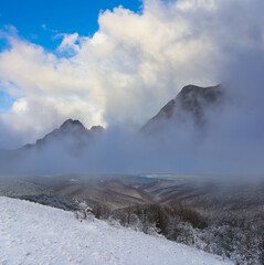 snowbound mountain ridge in mist and dense clouds