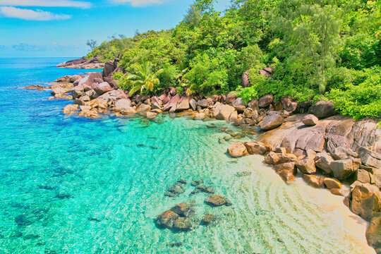  Drone shot of Anse Major beach, transparent sea, lush forest and granite stones, Mahe, Seychelles