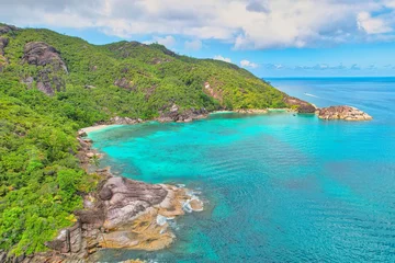 Foto op Plexiglas Drone shot of Anse du riz, rice beach beach, transparent sea, lush forest and granite stones, docked and passing boat, Mahe, Seychelles © Nils