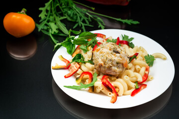 cooked pasta with meatballs, peppers and herbs with spices in a plate