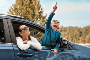 Happy family road trip, mother and son looking out of car window enjoying nature wildlife