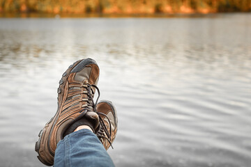 Person hiker resting his feet in a calm nature lake setting