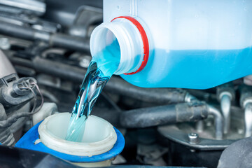 Close-up of pouring windshield wiper fluid in workshop. Checks and periodic maintenance of cars. - obrazy, fototapety, plakaty