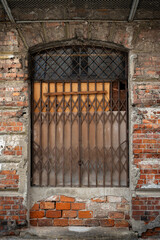 old brick wall with door with cast iron gratings