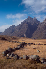 A group of rocks guide the eye towards a vast mountain range in the Peruvian highlands vertical