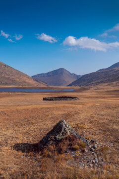 A triangular rock in a vally under a deep blue sky in the Andes