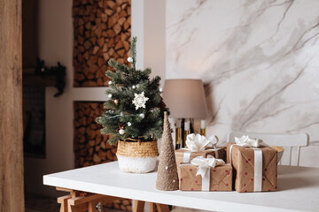 Wrapped in craft paper present boxes on table closeup and beautiful holdiay decorated room with ornaments and garland. Winter holiday background.Nordic-style bedroom