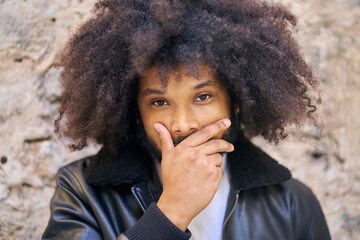 Fototapeta na wymiar close-up portrait of a young man with afro hair covering his mouth with his hand