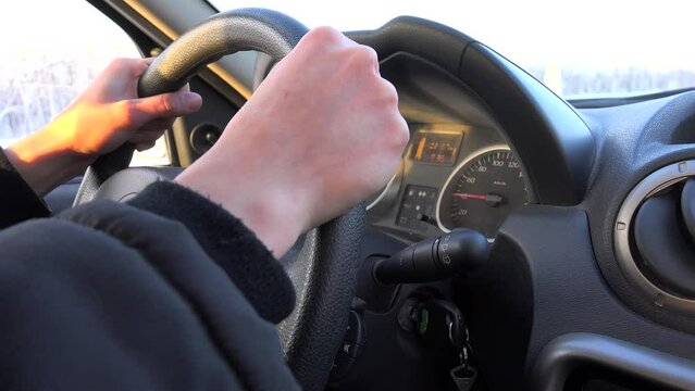 Driver's hands on the car steering wheel while driving in winter.  Stable 40 kmh (25 mph) on the speedometer.