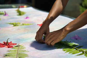 Hands placing leaves on cloth for pareo prints at workshop, Mahe Seychelles