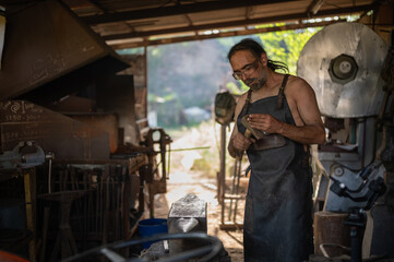 Blacksmith adjusting his hammer to work in his forge shop.