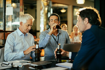Businessmen enjoying a casual meeting over drinks in a bar