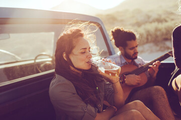 Friends sharing a musical moment during a sunlit road trip
