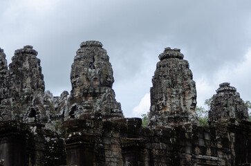 Fototapeta na wymiar Ancient Buddhist Temple Ruins of Angkor Wat in Siem Reap, Cambodia. Stone Carved Faces In Old Pillars.