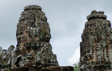 Fototapeta na wymiar Ancient Buddhist Temple Ruins of Angkor Wat in Siem Reap, Cambodia. Stone Carved Faces In Old Pillars.