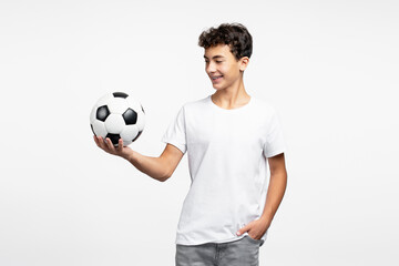 Portrait of smiling adult teenage boy wearing casual clothes holding soccer ball looking away