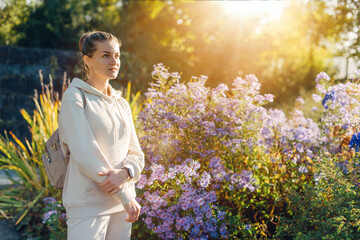 Beautiful elegant woman standing in autumn park with yellow leaves outdoor. Beauty Romantic Girl Outdoors enjoy autumn yellow leaves. Portrait of joyful woman in park during fall. Happy ng nature. Sun