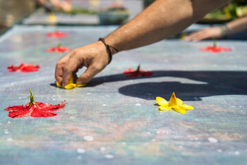 Man hand placing allamanda flower on cloth for pareo prints at workshop, Mahe Seychelles