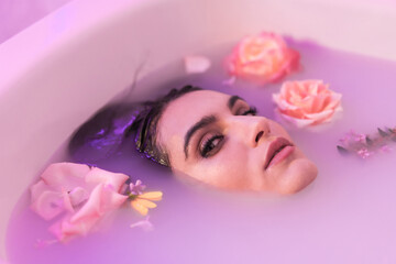 Obraz na płótnie Canvas Sensual woman in a bath milk with flowers