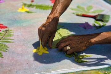 Man hand placing green fern on cloth for pareo, sarong  prints at workshop, Mahe Seychelles. 1