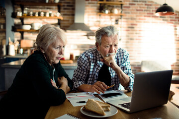 Senior couple doing bills and payments together in the kitchen at home