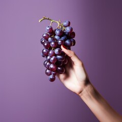 Woman's hand holding bunch of grapes on purple background, AI