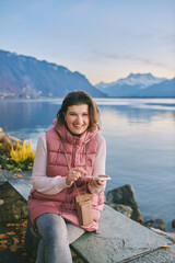 Fototapeta na wymiar Outdoor portrait of beautiful young woman relaxing by mountain lake, cold weather