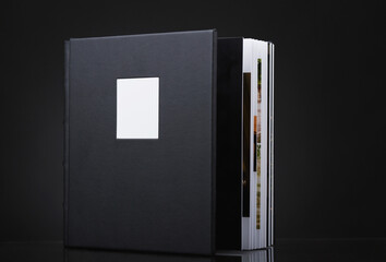 A beautiful leather bound books against a black background. Wedding photo book, family album. Stylish books on dark black background. The texture of the cover of a photobook made of genuine leather.