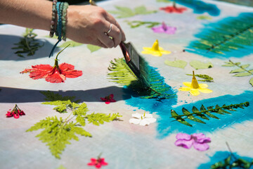 White skin woman hand, painting over leaves with cloth printing ink at workshop for her pareo making, Mahe Seychelles 1