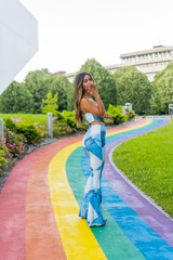 Woman blowing a kiss in a park with rainbow path
