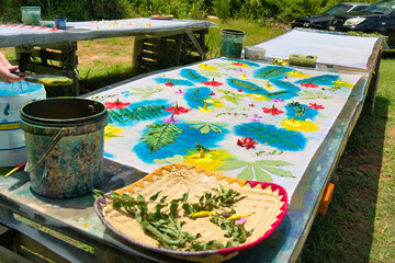 paint over leaves and flowers with cloth printing ink at workshop for her pareo making, Mahe...
