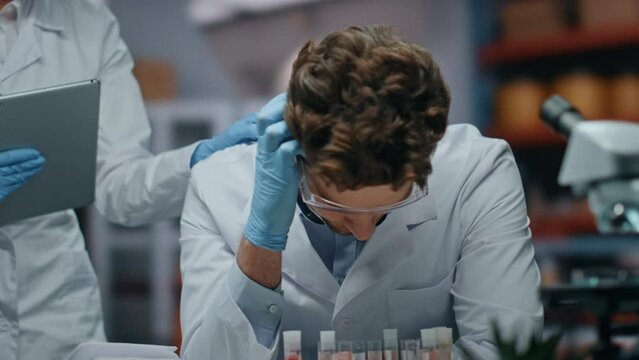 Sad scientist disappointed research failure in laboratory with colleague closeup