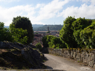 Vista de un paisaje con un camino rural rodeado de árboles verdes, cielo azul nubes blancas en...