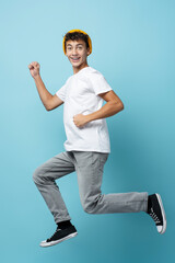 Fototapeta na wymiar Portrait of smiling boy with yellow hat, jumping, isolated on blue background, looking at camera