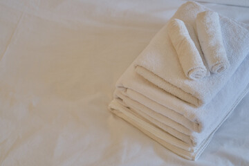 A stack of clean white towels on the bed. Hotel service. Place for text