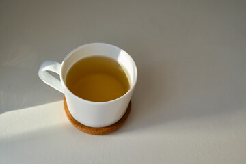 White cup with coffee or tea on the bed. Cozy morning photo. The concept is cozy and warm. Place for text